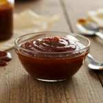 Glass bowl of Gordon Ramsay barbecue sauce on rustic wooden table