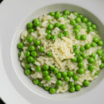 Gordon Ramsay Pea Risotto served in a white bowl with Parmesan and peas