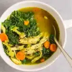 Healthy Chicken Kale Soup served in a rustic bowl with carrots and kale