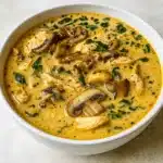 Bowl of Rotisserie Chicken Mushroom Soup with Creamy Garlic on wooden table