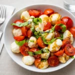 easy caprese salad with cherry tomatoes on white plate