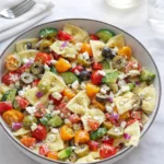 Greek pasta salad in a bowl with tomatoes, cucumbers, olives, and feta