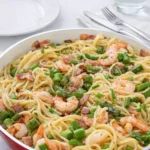 Shrimp Asparagus Carbonara in a white bowl with bacon and asparagus