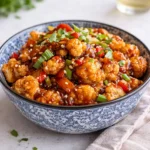 Crispy Kung Pao Cauliflower served over rice with peanuts and green onions.