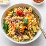 A steaming bowl of Roasted Veggie Pasta with Feta featuring colorful roasted vegetables