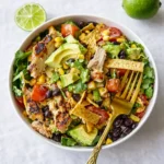 A colorful Southwestern Chopped Chicken Salad in a wooden bowl on a white counter.