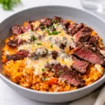A bowl of Steak Queso Rice with creamy cheese sauce and cilantro.