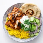 Tandoori Chicken with rice and naan on wooden table