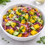 A colorful bowl of Tropical Cucumber Mango Slaw with lime and cilantro.