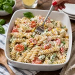 A colorful bowl of Creamy Italian Pasta Salad on a wooden table.