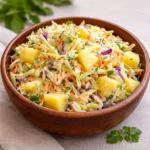 A colorful bowl of fresh Pineapple Slaw with cabbage and carrots.