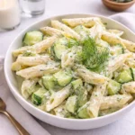 A bowl of Healthy Cucumber Pasta Salad with creamy dill dressing on a wooden table.