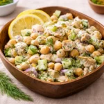 A fresh Healthy Tuna Garbanzo Bean Salad in a white bowl with lemon and dill.