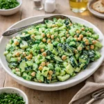 A fresh Sunshine Salad with chickpeas and tahini dressing in a white bowl.
