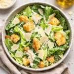 The Best Homemade Caesar Salad in a wooden bowl on a marble counter.