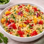 The Best Orzo Salad in a white bowl with fresh vegetables.