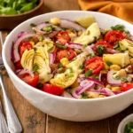 Fresh Tuscan Artichoke Tomato Salad in a white bowl on a wooden table.